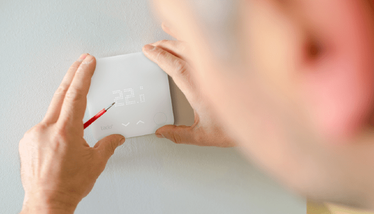 Close up image of the back of a man's head who is is fitting a Tado thermostat