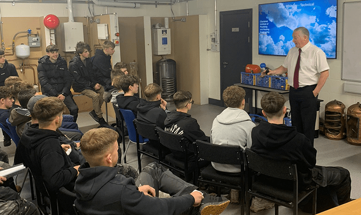 A classroom full of young male plumbing apprentices listening to a lecture